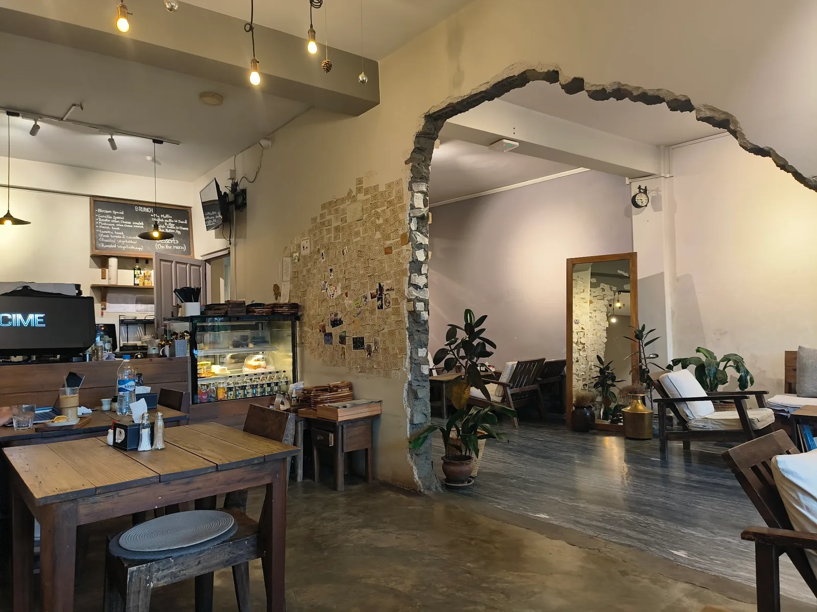 The minimalist interior of Cafe Camellia — wooden tables, a stone archway, the espresso bar