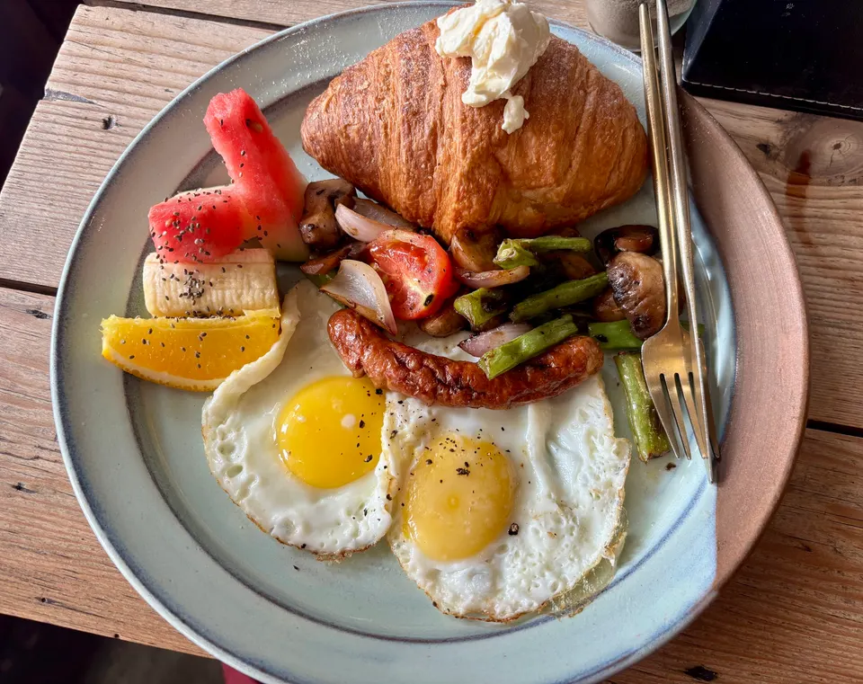 Camellia breakfast — fried eggs, croissant, vegetables on a stone plate